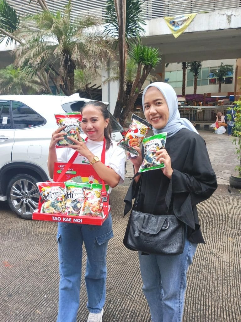SPG melakukan sampling selling Taokaenoi kepada pengunjung pasar