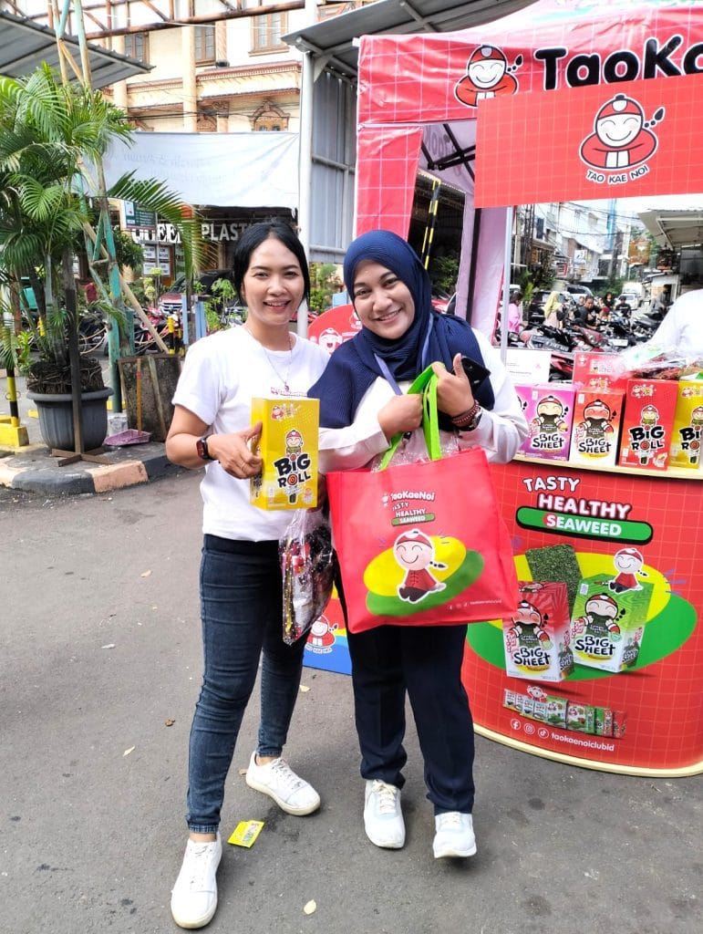 SPG melakukan sampling produk Taokaenoi kepada pengunjung pasar